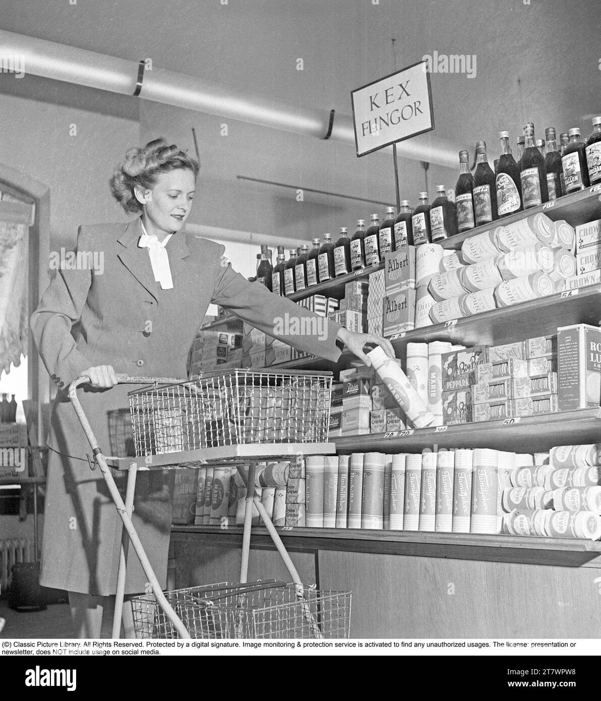 Shopping in den 1940er Jahren Eine Frau kauft in einem Selbstbedienungsladen ein. Sowohl die Idee des Self-Service als auch der Einkaufswagen kamen aus Amerika und zielten darauf ab, den Umsatz zu steigern. Der Kunde konnte sich die Lebensmittel aussuchen, in den Einkaufswagen legen und zur Kasse gehen. Zu dieser Zeit wurde diese Art des modernen Einkaufs in Schweden neu eingeführt. 1949. Kristoffersson Ref. AS47-4 Stockfoto