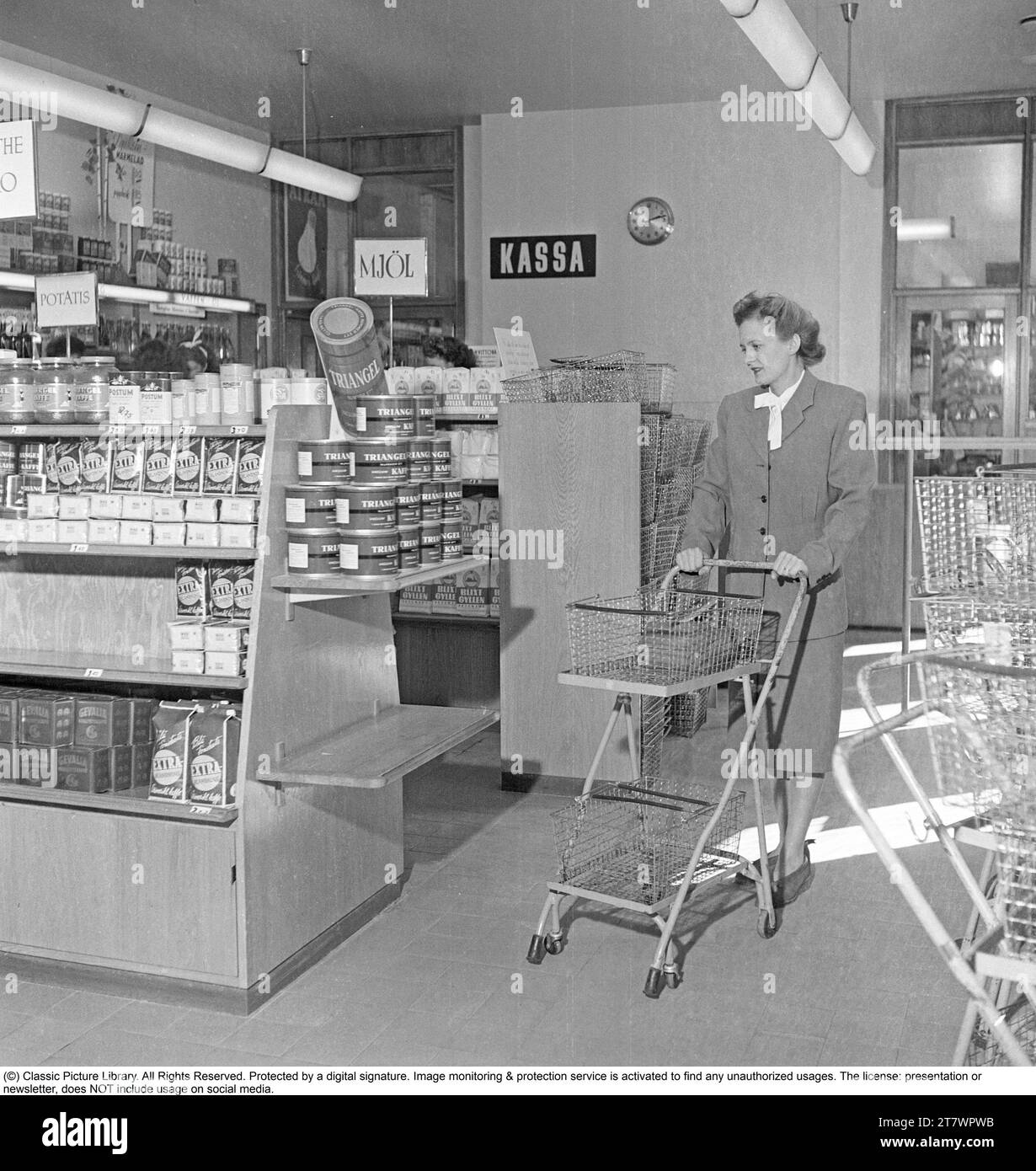 Shopping in den 1940er Jahren Eine Frau kauft in einem Selbstbedienungsladen ein. Sowohl die Idee des Self-Service als auch der Einkaufswagen kamen aus Amerika und zielten darauf ab, den Umsatz zu steigern. Der Kunde konnte sich die Lebensmittel aussuchen, in den Einkaufswagen legen und zur Kasse gehen. Zu dieser Zeit wurde diese Art des modernen Einkaufs in Schweden neu eingeführt. 1949. Kristoffersson Ref. AS47-5 Stockfoto