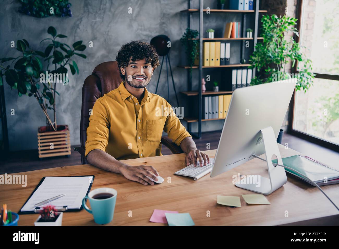 Foto-Porträt des hübschen jungen Mannes tragen gelbes Hemd fröhliches Startup Administrator Arbeitsplatz stilvoller Raum Innenraum Home Office Design Stockfoto