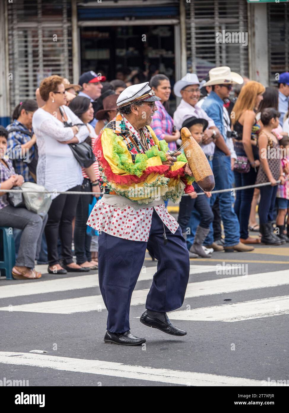 Farbenfroher Mann tanzt während er einen Guiro in einer Parade in San José, Costa Rica spielt. Stockfoto