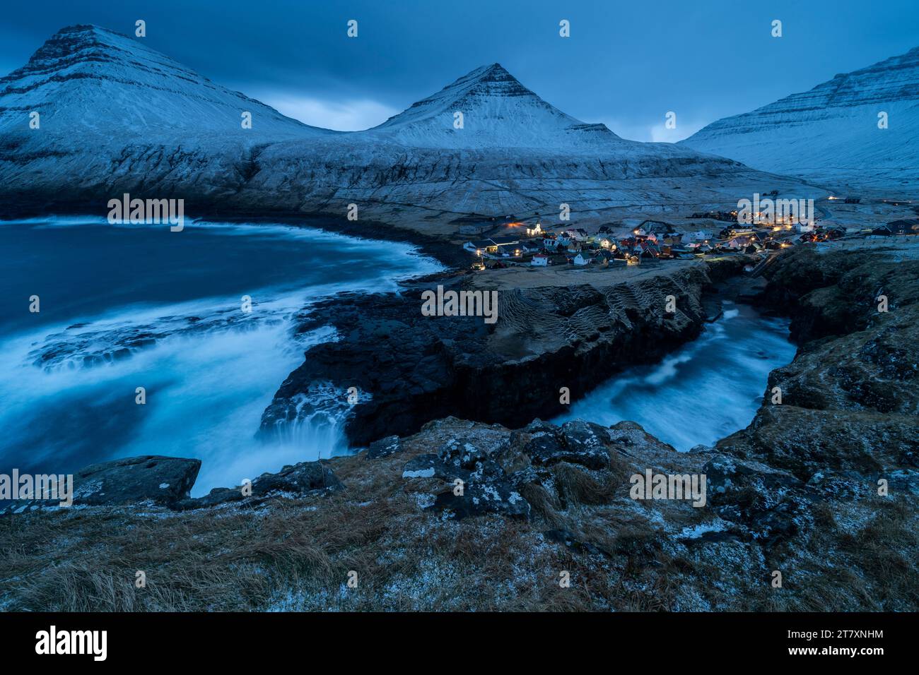 Dorf Gjogv und schneebedeckte Berge in der Abenddämmerung, Gjogv, Eysturoy, Färöer, Dänemark, Europa Stockfoto