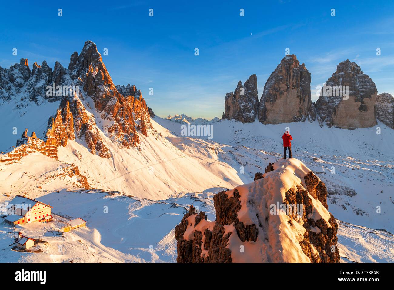Rückansicht eines Wanderers, der die drei Zinnen von Lavaredo (drei Zinnen) von der Spitze eines riesigen Felsens bewundert, Blick auf den Winter, Sexten (Sexten) Stockfoto