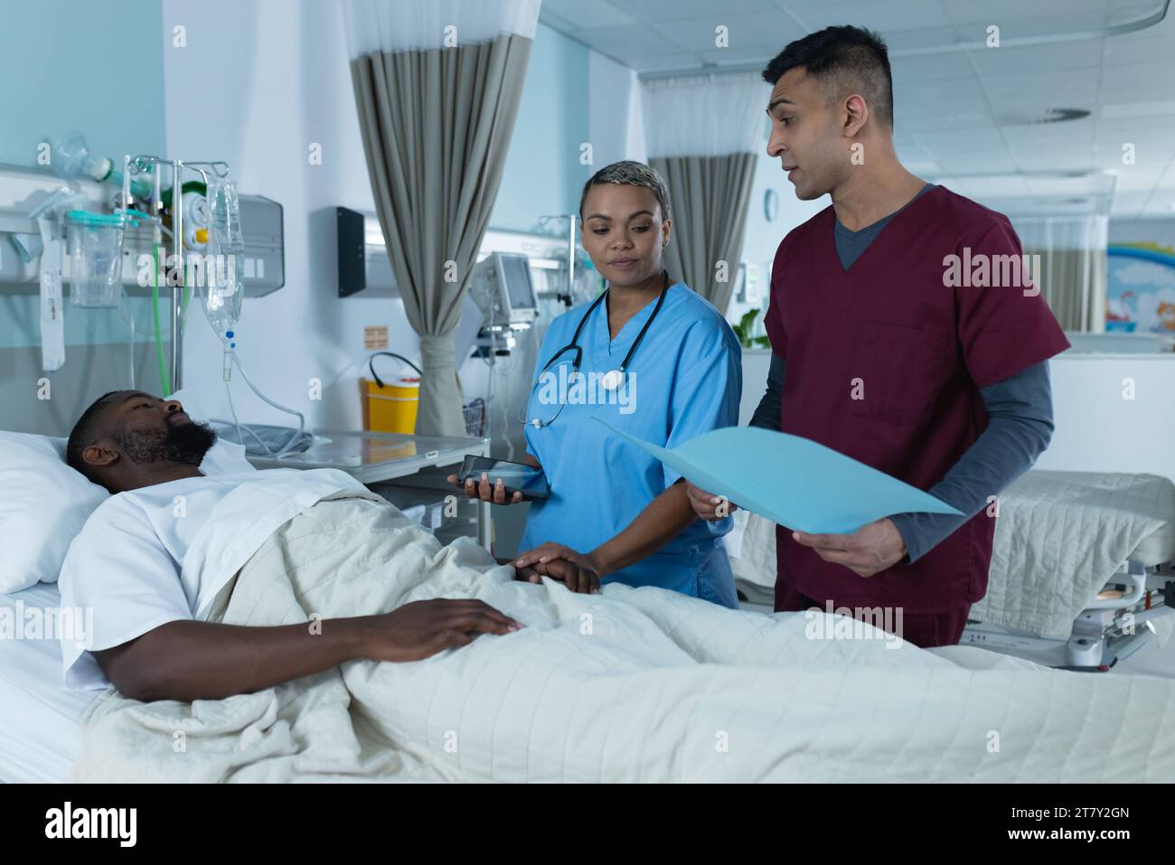 Verschiedene Ärzte und männliche Patienten liegen im Bett und reden im Krankenhauszimmer Stockfoto