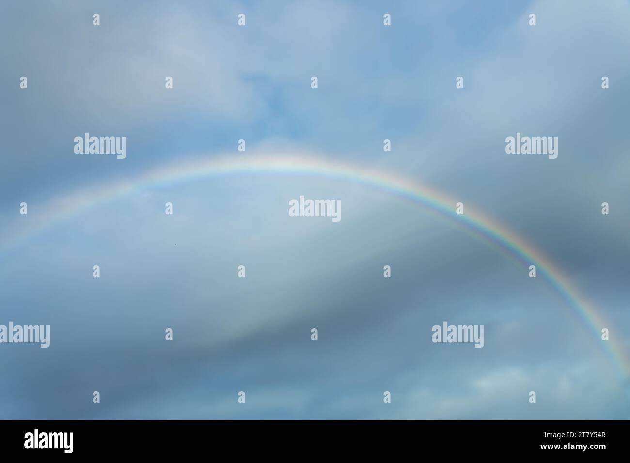 Echtes Foto eines Regenbogens am Himmel mit Wolken und blauem Himmel Stockfoto