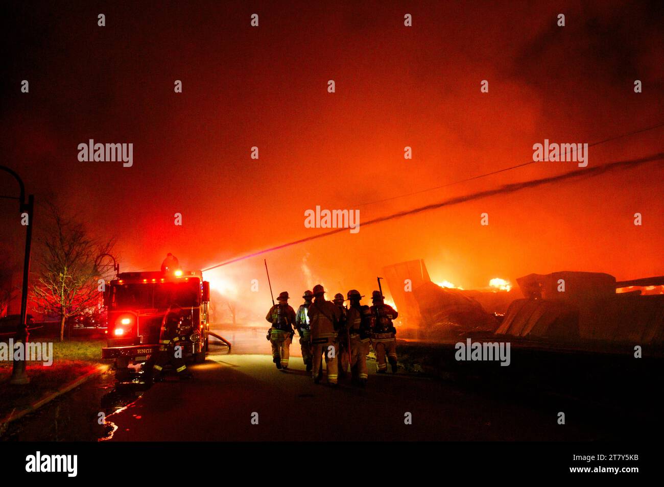 Feuerwehrmänner im Kampf gegen eine spektakuläre Flamme auf dem RK Miles Holzlager in Montpelier, VT, New England, USA. Stockfoto