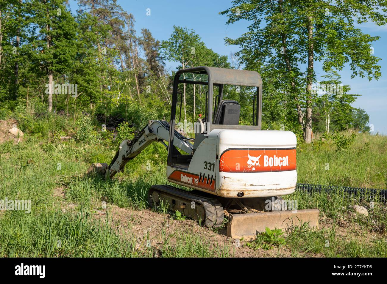 CROW WING CO - 8. JUN 2023: Ein Minibagger der Marke Bobcat parkt auf dem Grundstück eines zukünftigen Wohnhauses. Stockfoto