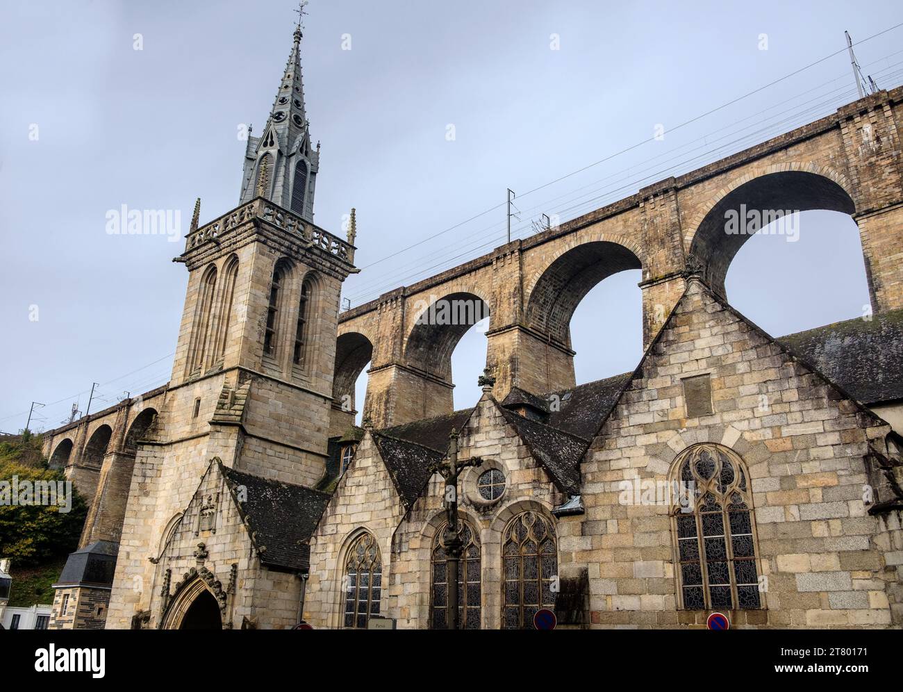 Der Turm von Eglise Saint-Melaine unter dem Eisenbahnviadukt im Stadtzentrum von Morlaix, Bretagne, Frankreich Stockfoto