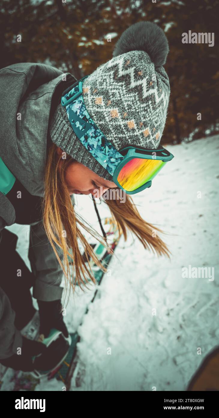 Ein junger Erwachsener Snowboarden eine Winterpiste hinunter, ausgestattet mit Schutzbrille und Handschuhen zum Schutz Stockfoto