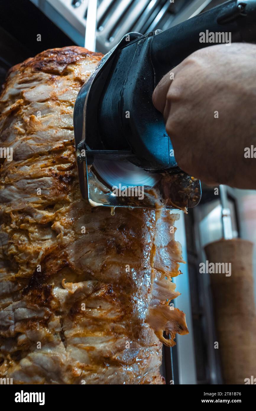 Der Koch schneidet Kebab-Brötchen mit einem Hobel Stockfoto