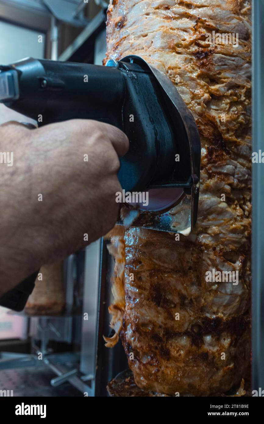 Nahaufnahme einer Hand schneidet Kebab-Rolle mit einem Hobel Stockfoto