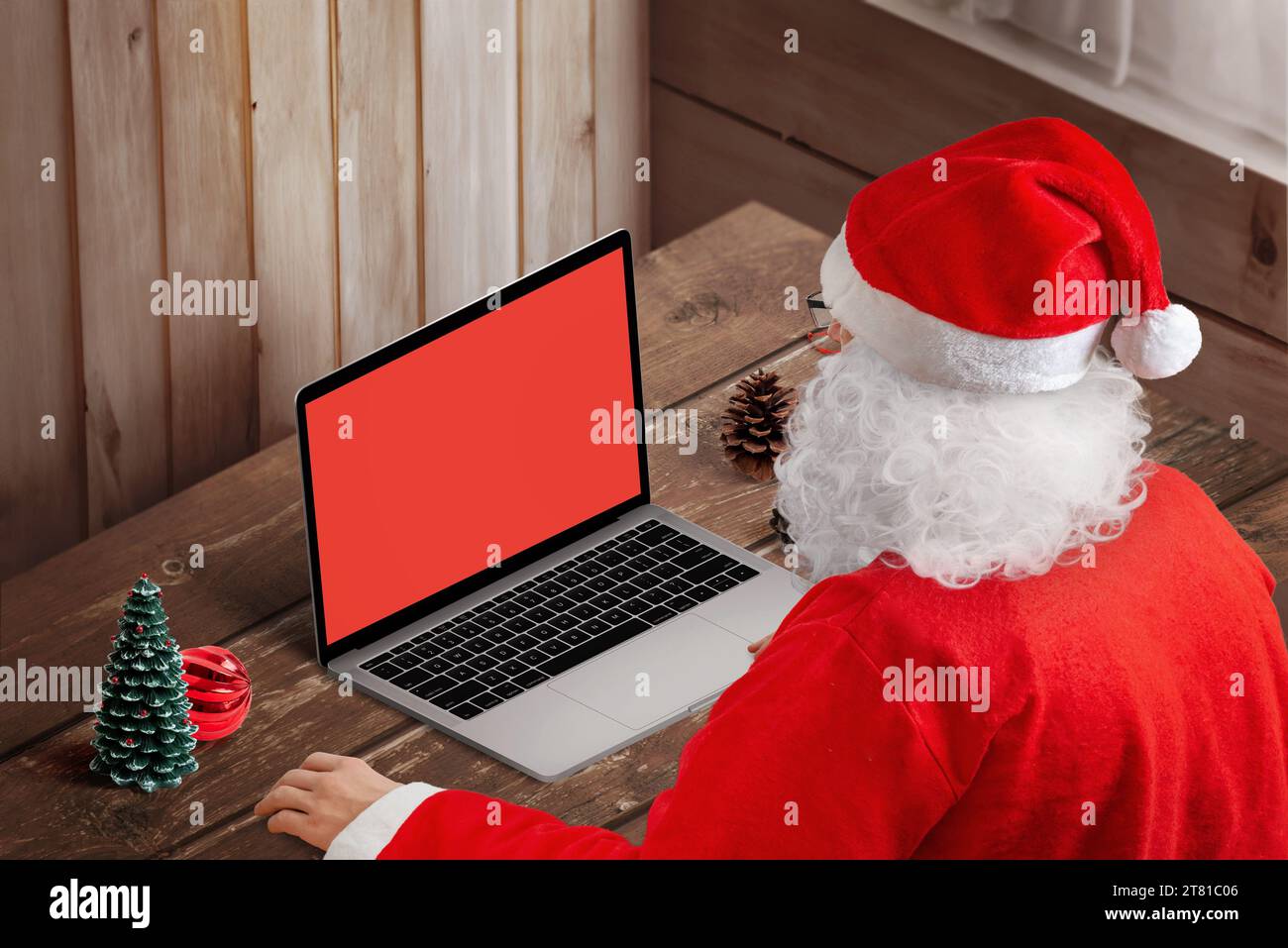 Weihnachtsmann tippt zu Hause auf einem Laptop. Isolierter Bildschirm für Mockup, Kopie, Webseite oder App-Präsentation. Festliche Technik Stockfoto