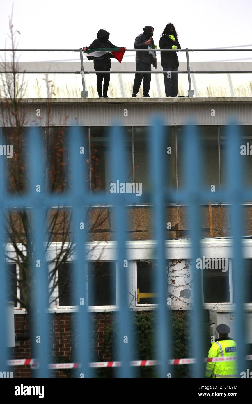 Southampton, Hampshire, Großbritannien. November 2023. Aktivist hält palästinensische Fahnen, während ein Polizist in einem abgesperrten Gebiet am Boden versucht, sie niederzureden. Palästina-Aktion besetzt das Dach der italienischen Rüstungsindustrie, der Riese Leonardo in seiner Fabrik in Southampton. Leonardo beliefert Israel mit Kampfjets und Waffen, die derzeit im Gazastreifen eingesetzt werden. Palestine Action verlangt, dass Waffenunternehmen, die Waffen für Israel bereitstellen, dauerhaft geschlossen werden. Sie haben angekündigt, dass Unternehmen, die Waffen an die israelischen Streitkräfte verkaufen, und ihre Partnerunternehmen dies tun werden Stockfoto