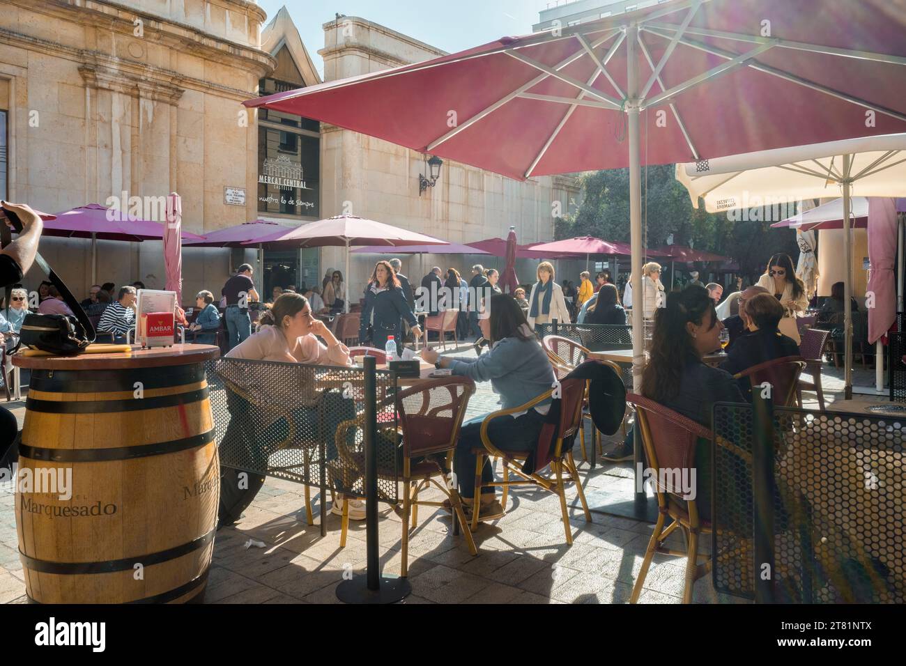 Die Gäste sitzen auf der Terrasse einer Bar mit Stühlen, Tischen und Sonnenschirmen auf dem Pescadería-Platz des zentralen Marktes der Stadt Castellon Stockfoto