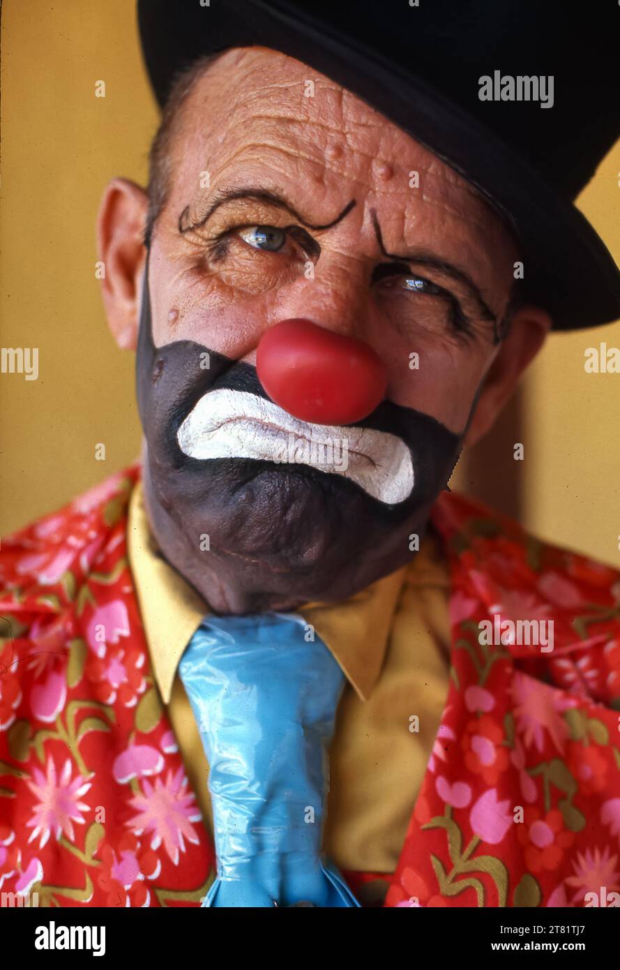 Trauriger Clown, bunte Jacke, Krawatte, Hut und knallrote Nase. Stockfoto