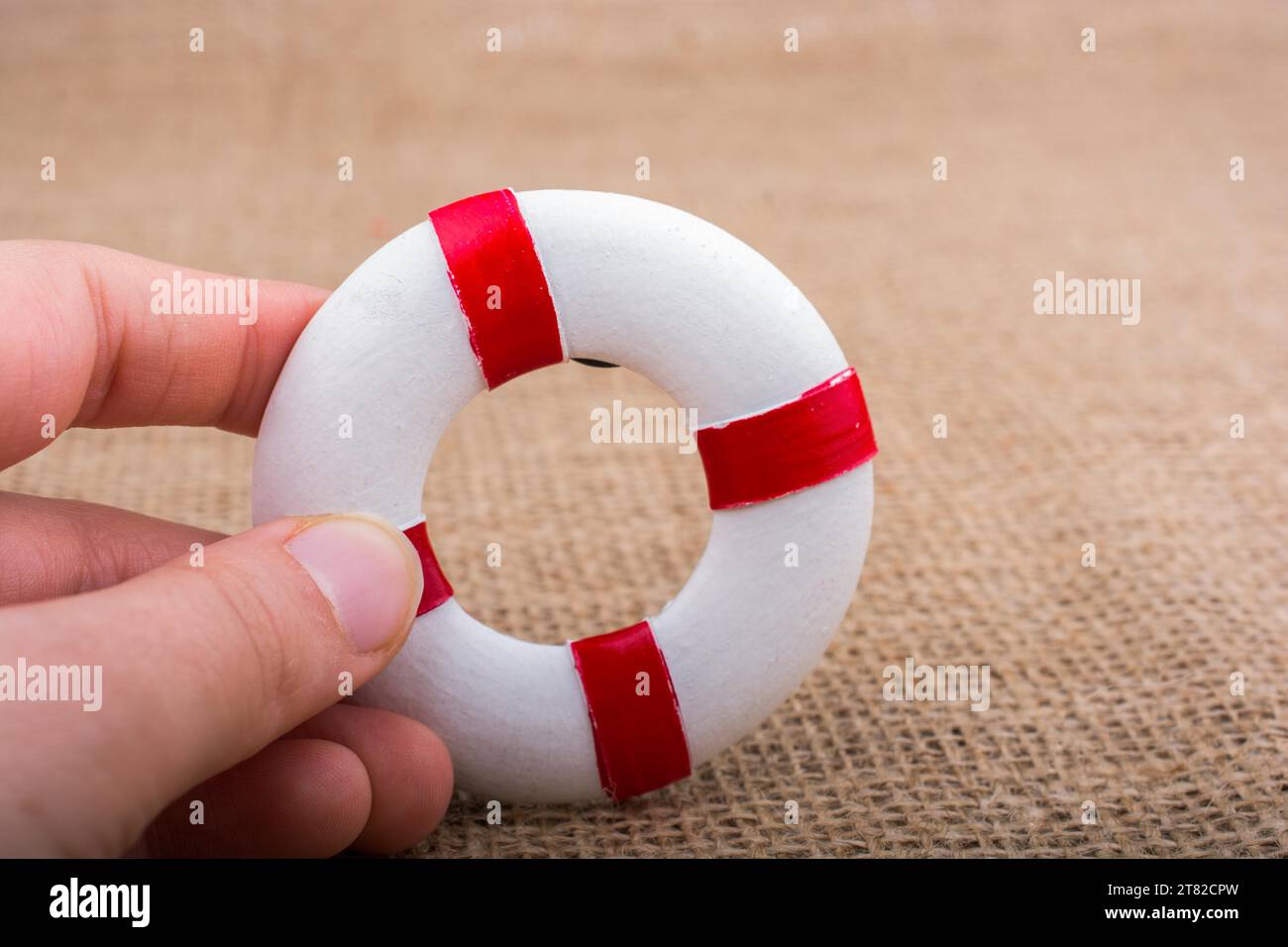 Hand, die einen Lifesaver oder eine Rettungsweste auf einem Stoffhintergrund hält Stockfoto