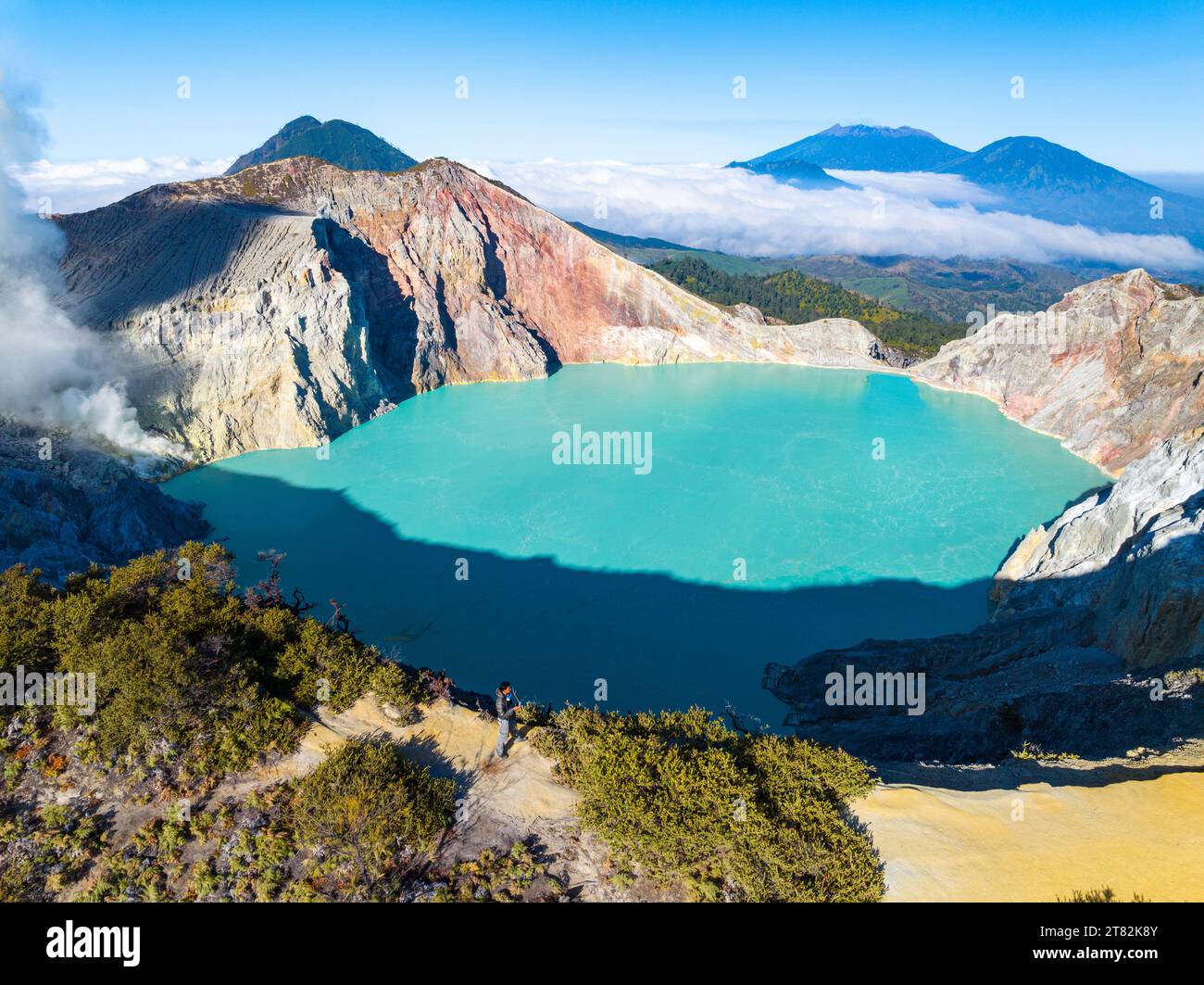 Aus der Vogelperspektive auf die Felsenklippe am Kawah Ijen Vulkan mit türkisfarbenem Schwefelwassersee bei Sonnenaufgang. Fantastischer Blick auf die Naturlandschaft in Ost-Java, Indonesien. Natu Stockfoto
