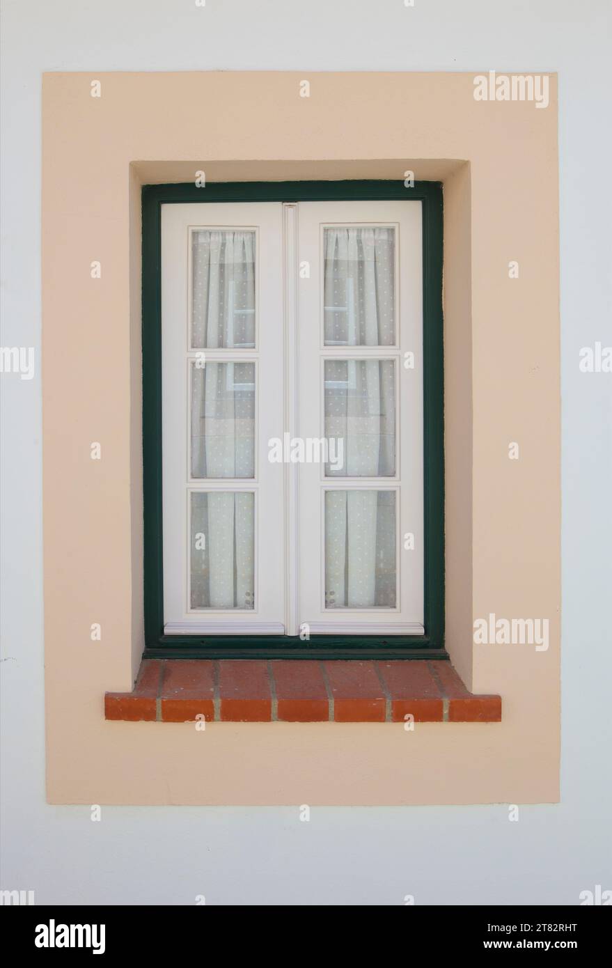 Winziges Fenster mit lebhaften Farben im Haus Vila Nova de Milfontes. Kleine malerische Stadt an der Küste von Alentejo, Portugal Stockfoto