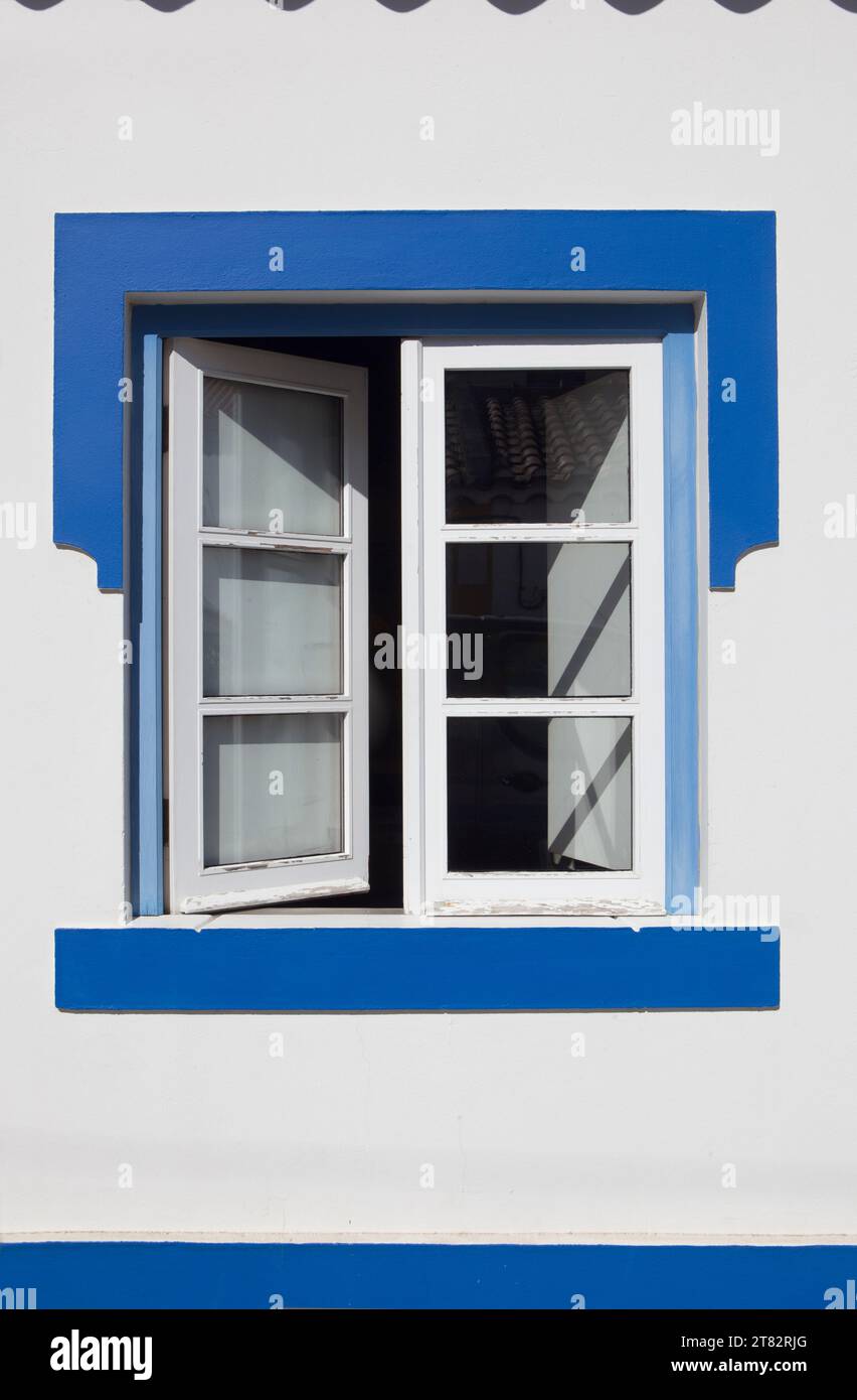 Winziges Fenster mit lebhaften Farben im Haus Vila Nova de Milfontes. Kleine malerische Stadt an der Küste von Alentejo, Portugal Stockfoto