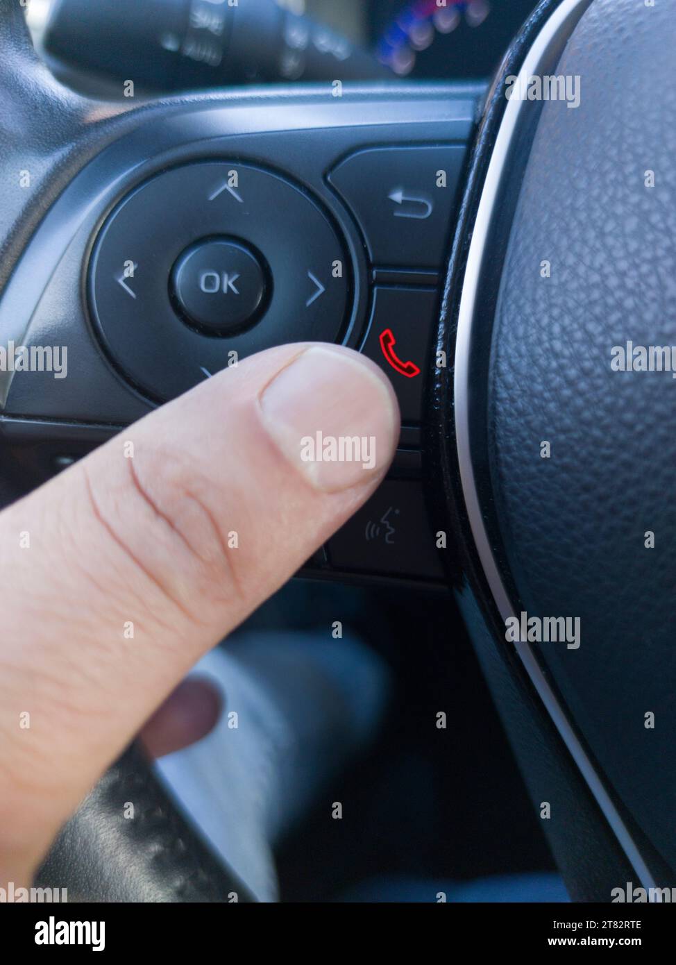 Fahrer, der das Telefon über die Lenkradtasten auflegt. Verwenden eines Telefons während der Fahrt Stockfoto