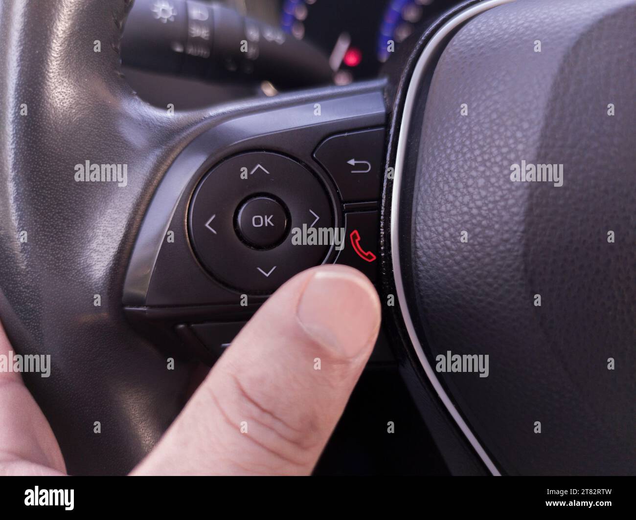 Fahrer, der das Telefon über die Lenkradtasten auflegt. Verwenden eines Telefons während der Fahrt Stockfoto