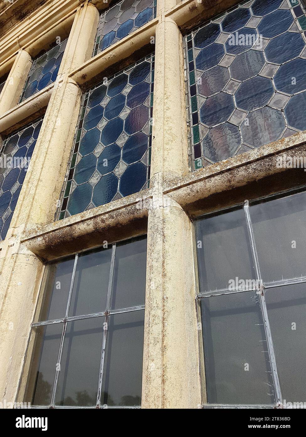Nahaufnahme eines historischen dekorativen Fensters, das in eine Steinmauer eingefasst ist. Stockfoto