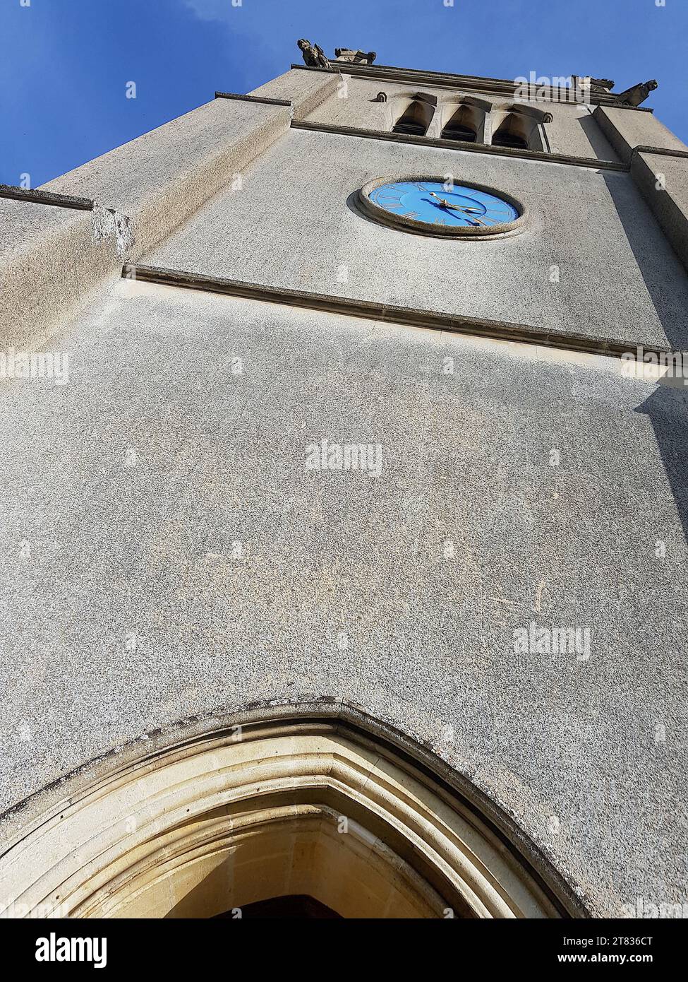 Nahaufnahme eines historischen Kirchturms aus Stein vor einem hellblauen Himmel. Stockfoto