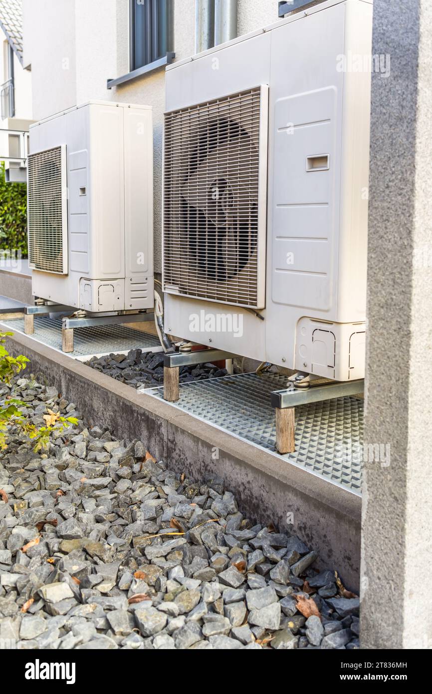 Zwei Luftquellenwärmepumpen außerhalb des modernen Familienhauses installiert, Konzept der Wärmepumpe für umweltfreundliche erneuerbare Energien Stockfoto