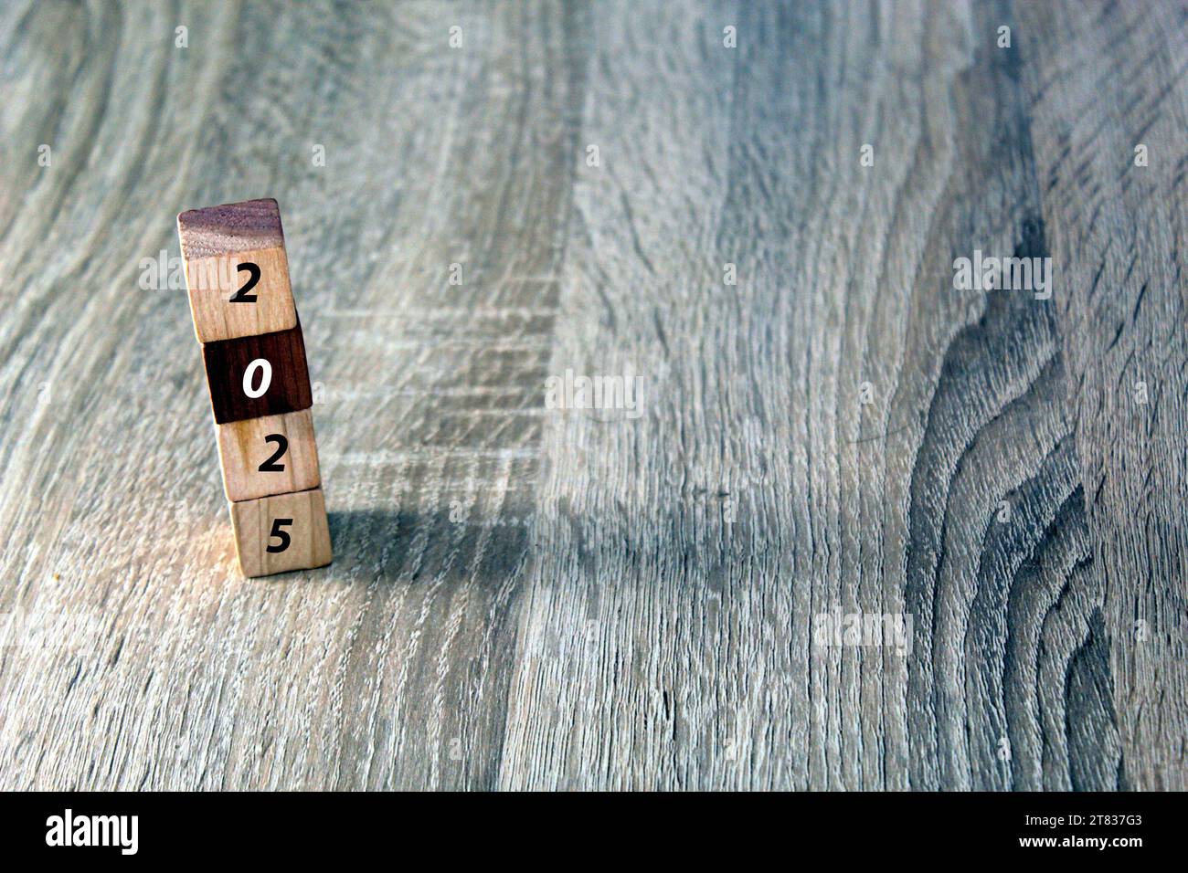 Holzwürfel mit 2025 und Happy New Year über hölzernem Hintergrund, Banner mit Kopierraum für Text, Neujahrsgrußkarte Vorlage Stockfoto
