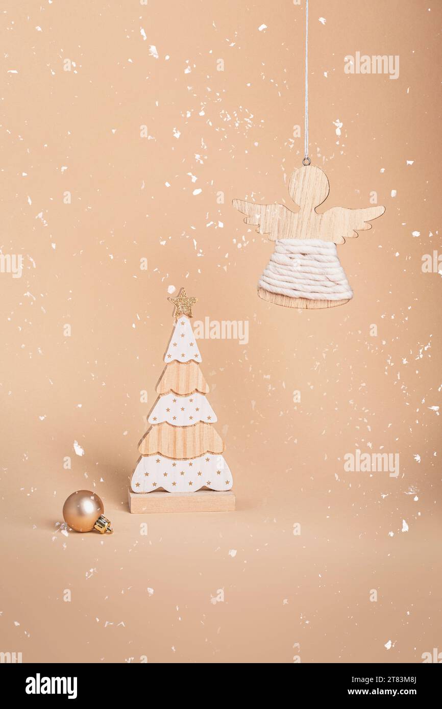 Holzspielzeug aus Tannenholz und Engelsfigur auf neutralem beigefarbenem Hintergrund. Weihnachtskonzept, Weihnachtsdekoration. Nahaufnahme. Stockfoto