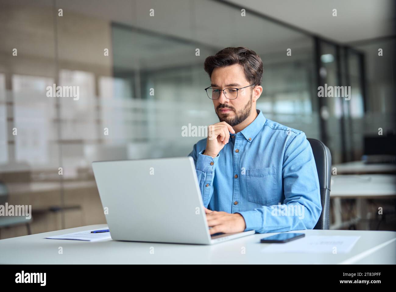 Ein geschäftiger Geschäftsmann denkt über das Online-Investment-Management nach und arbeitet an einem Notebook. Stockfoto