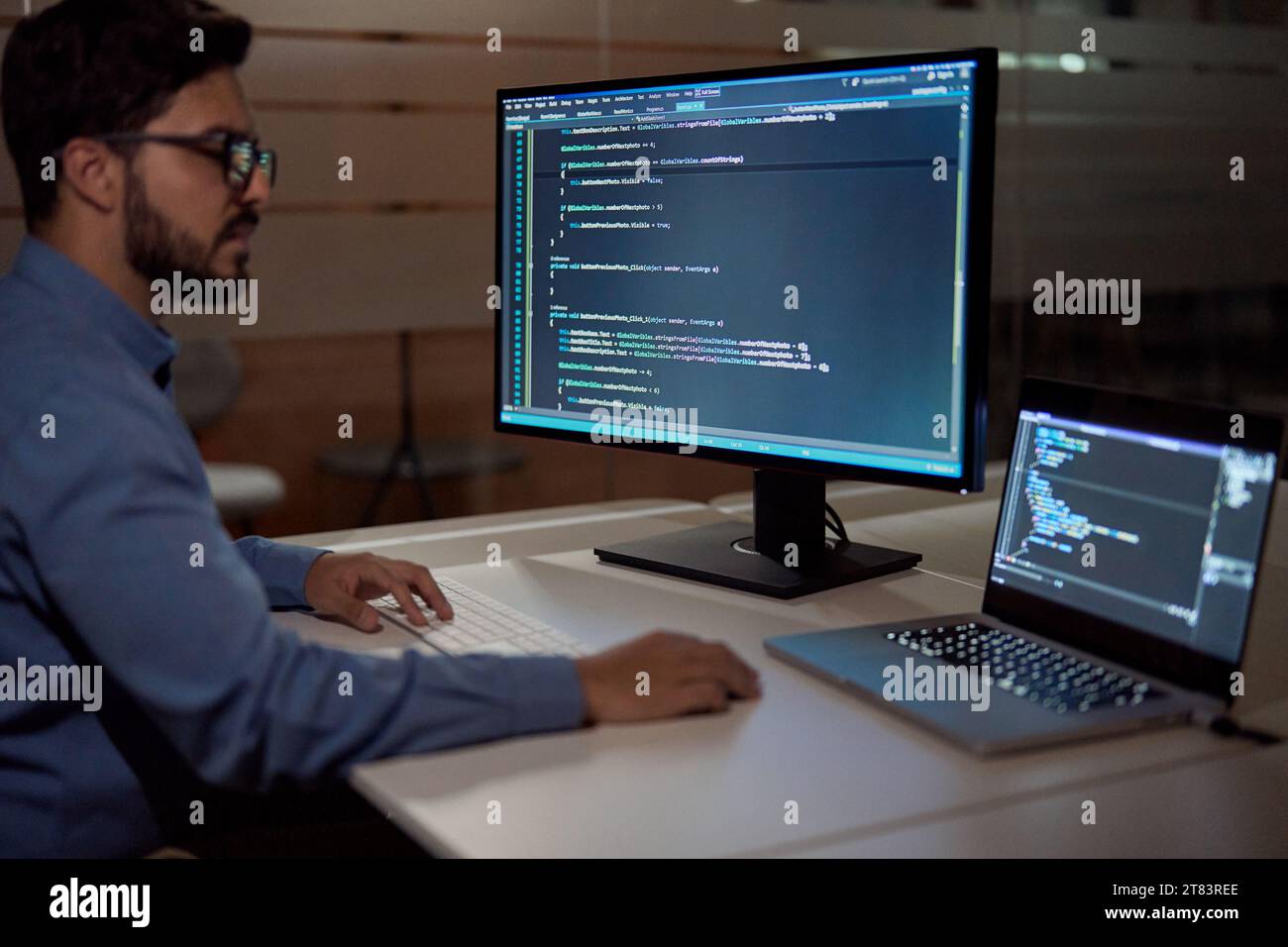 Softwareentwickler, der spät am Computer im dunklen Büro arbeitet. Stockfoto
