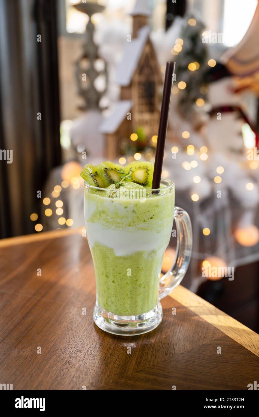 Kiwi-Saft-Milchshake-Smoothie im Glas auf Holztisch und heller Bokeh-Hintergrund Stockfoto