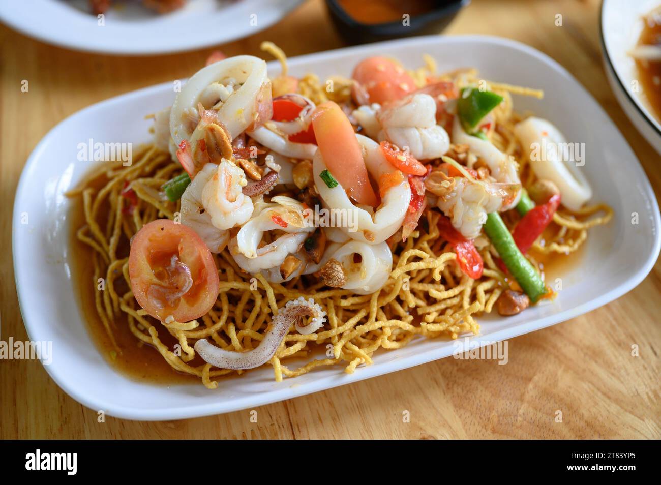 Knusprige Nudeln mit würzigem Salat und Meeresfrüchten. Vorspeise mit thailändischem Essen Stockfoto
