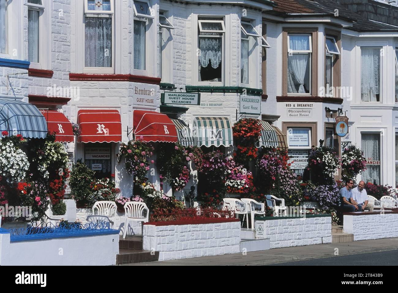 Bunte, hängende Körbe mit Blumen entlang einer Reihe von Gästehäusern. Trafalgar Road, Great Yarmouth, Norfolk, England, Großbritannien Stockfoto