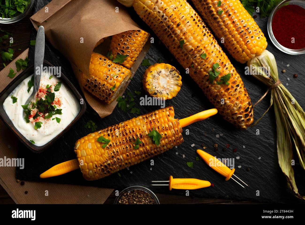 Gegrillter Mais auf dem Kolben in kaukasischen Händen auf Küche Holztisch Hintergrund Stockfoto