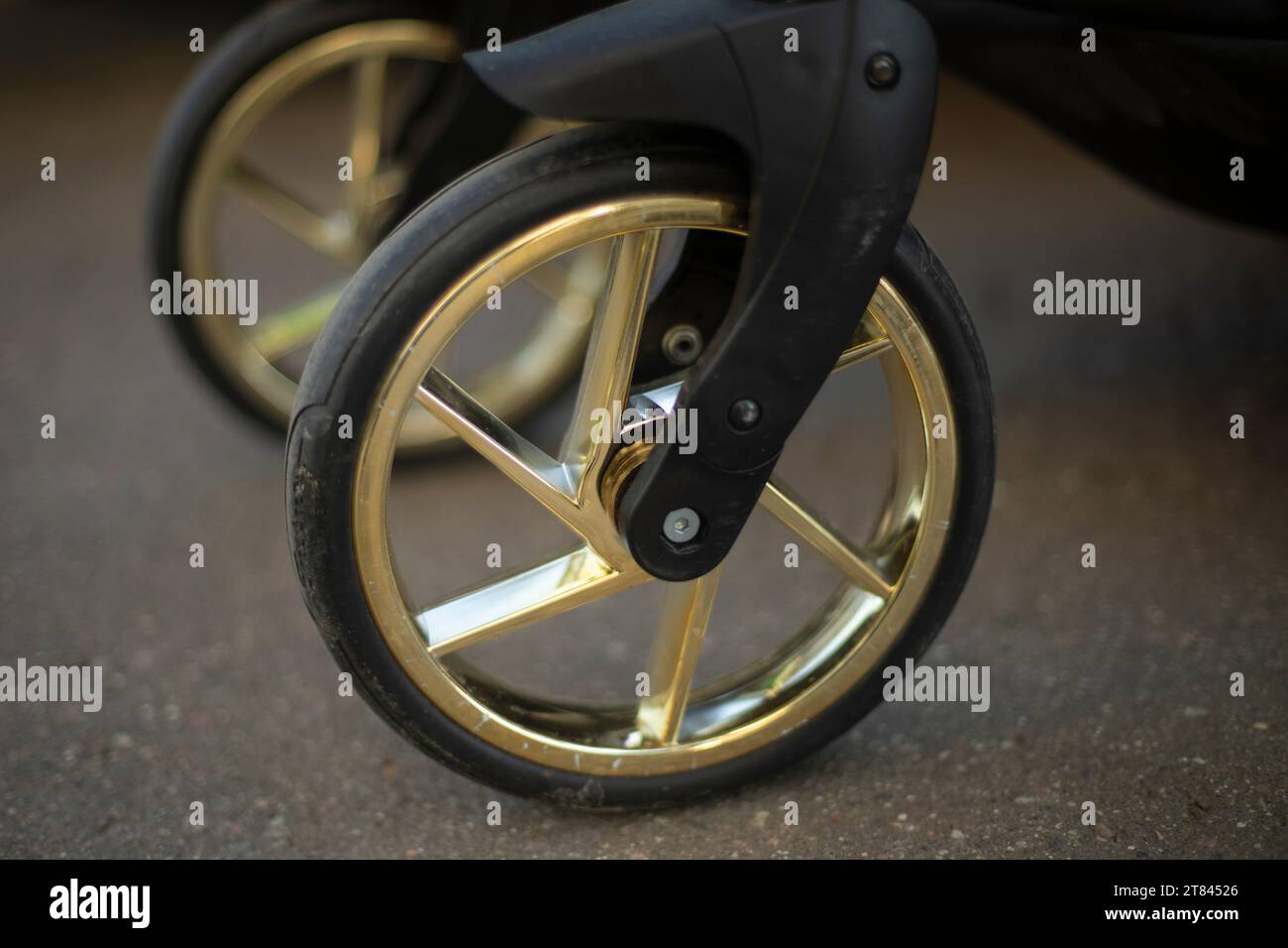 Kinderwagen. Goldenes Felgenrad. Details zum Kinderwagen. Gummirad. Stockfoto