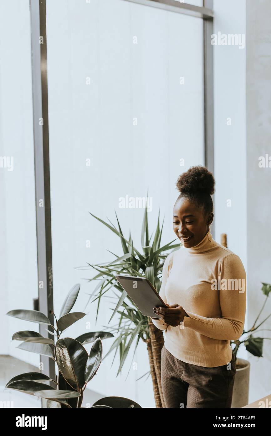 Eine hübsche junge afroamerikanische Geschäftsfrau mit einem digitalen Tablet im Büro Stockfoto