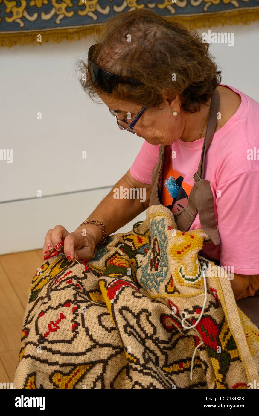 Frau stickt Wandteppiche in traditioneller Weise und entwirft im Wandteppiemuseum in Arraiolos, Portugal einen Teppich Arraiolos, Wandteppiche Arraiolos, AR Stockfoto