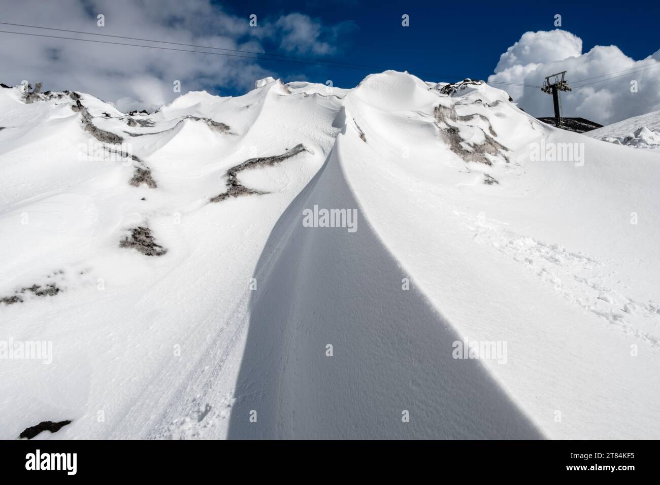 Schneesuppe auf dem Vulkan Ätna im Winter, Insel Sizilien, Italien. Nahaufnahme der Schneelage auf Vulkanhängen mit schwarzen Lavasteinen unter Blau Stockfoto