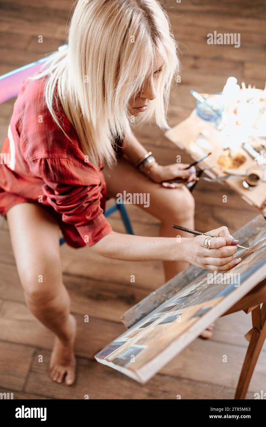 Junge, blonde Frau malte in ihrem Atelier Stockfoto
