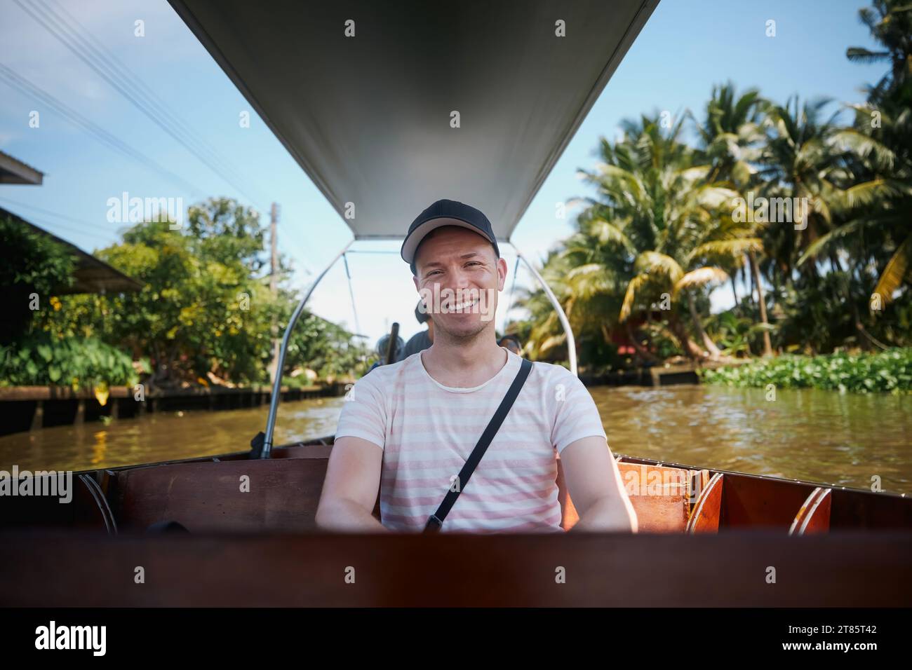 Porträt eines lächelnden Touristen auf dem Boot. Man genießt Urlaub auf einem Bootsausflug zum schwimmenden Markt Damnoen Saduak in Ratchaburi in der Nähe von Bangkok, Thailand. Stockfoto