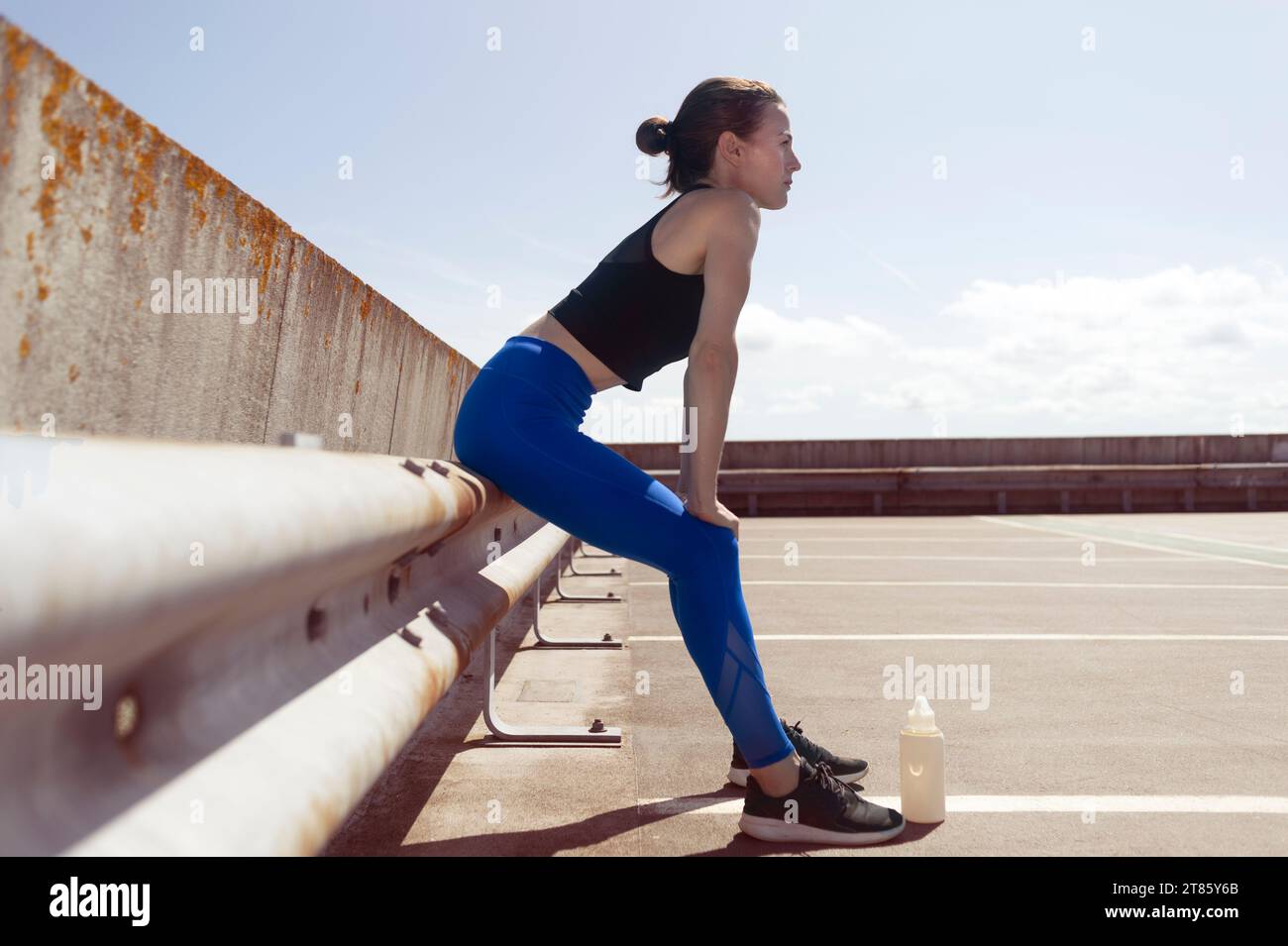 Sportliche Frau in Sportbekleidung, die nach dem Joggen ruht und Hände auf die Knie legt Stockfoto