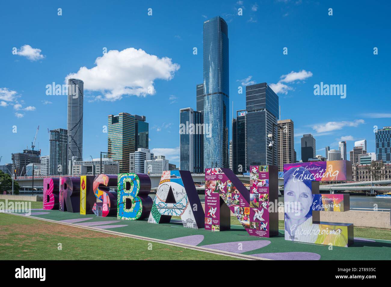 Ein Blick von vor dem „Brisbane“-Schild auf dem South Bank Cultural Presinct an einem Tag mit weißer Wolke und blauem Himmel und den hohen Wolkenkratzern des CBD. Stockfoto