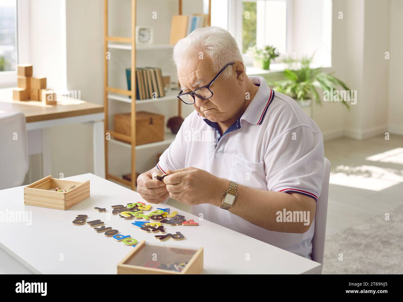 Ein älterer Mann sammelt ein Puzzle für ein gfvznb-Workout. Stockfoto