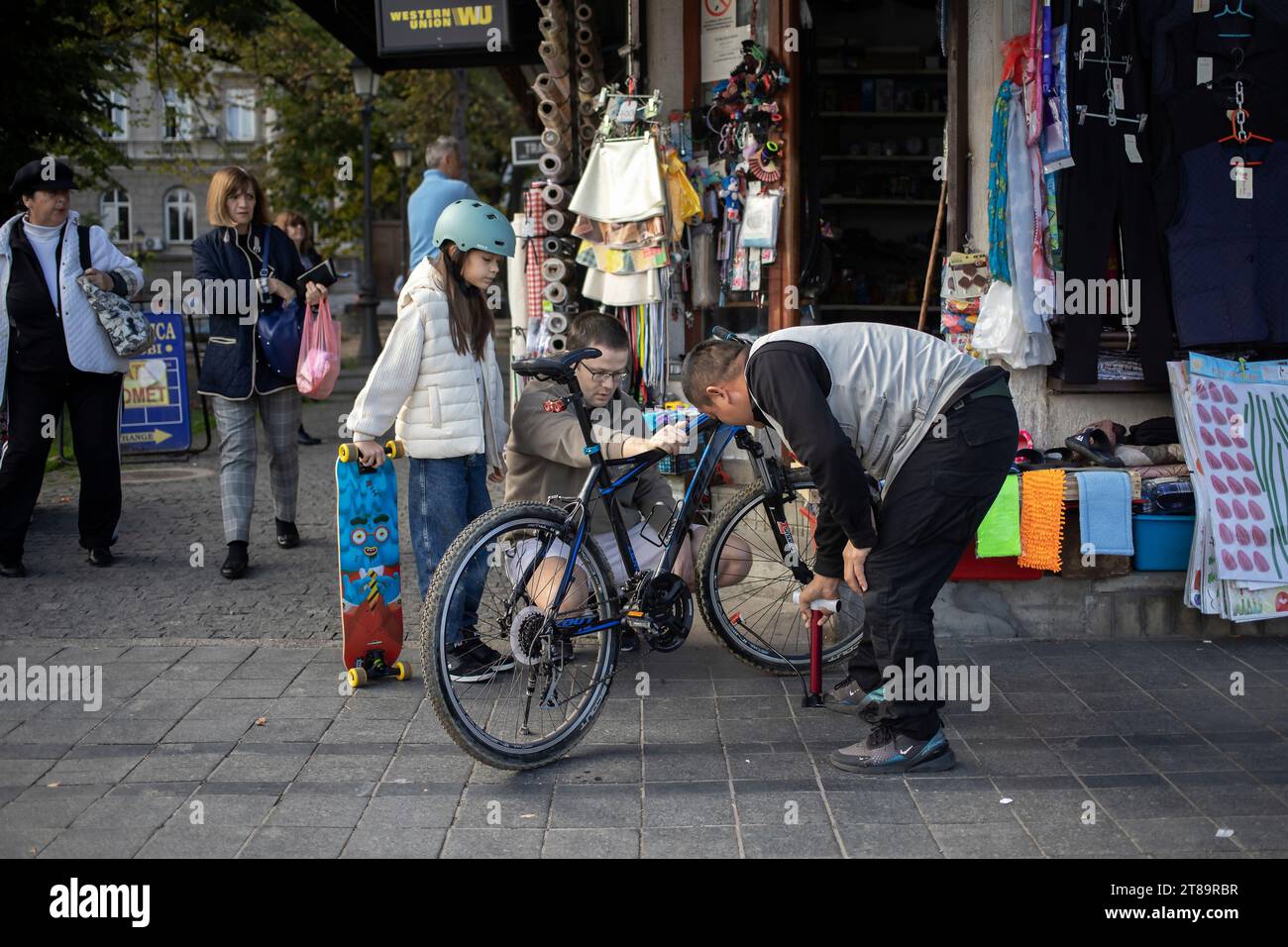 Belgrad, Serbien, 7. November 2023: Ein Verkäufer aus einem lokalen Geschäft hilft einem Mann mit einer Tochter, ein Fahrrad zu reparieren Stockfoto