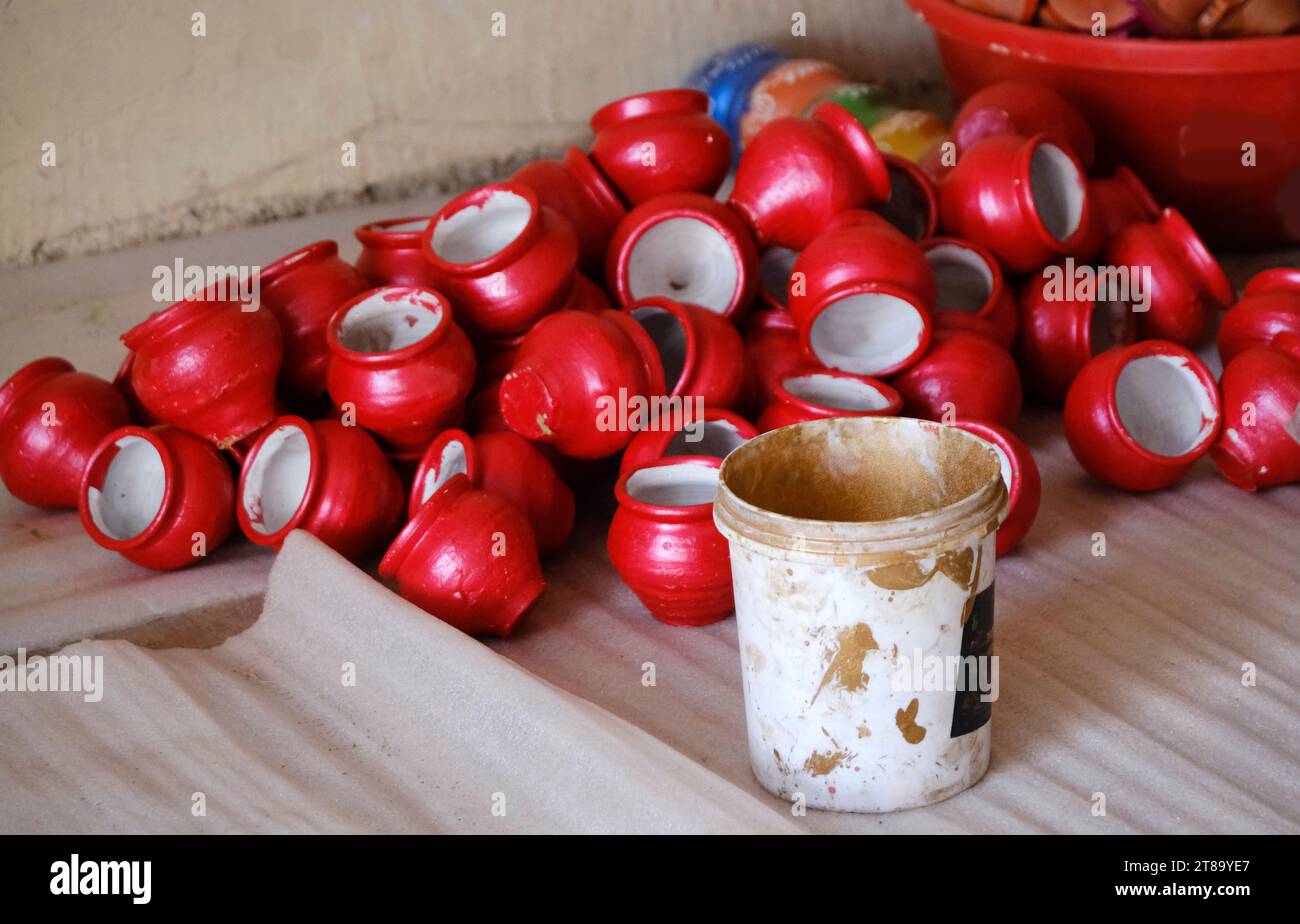 An Potter trägt Farbe auf Steingut-Öltöpfe oder Diyas in einer Werkstatt vor dem bevorstehenden Diwali-Festival, dem Hindu-Lichterfest, auf. Stockfoto