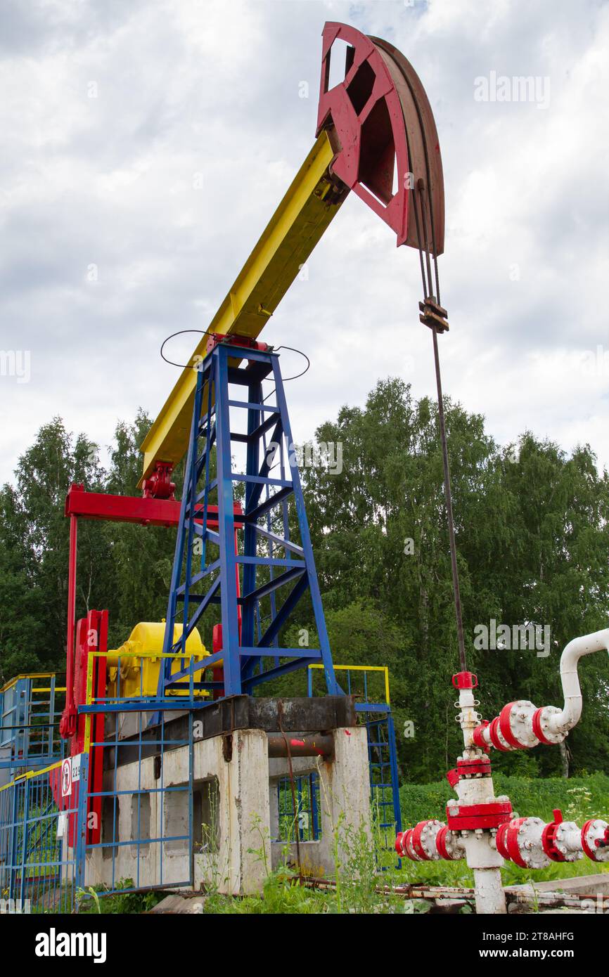 Die Ölpumpe steht auf einem Ölfeld in einem Sommerwald Stockfoto