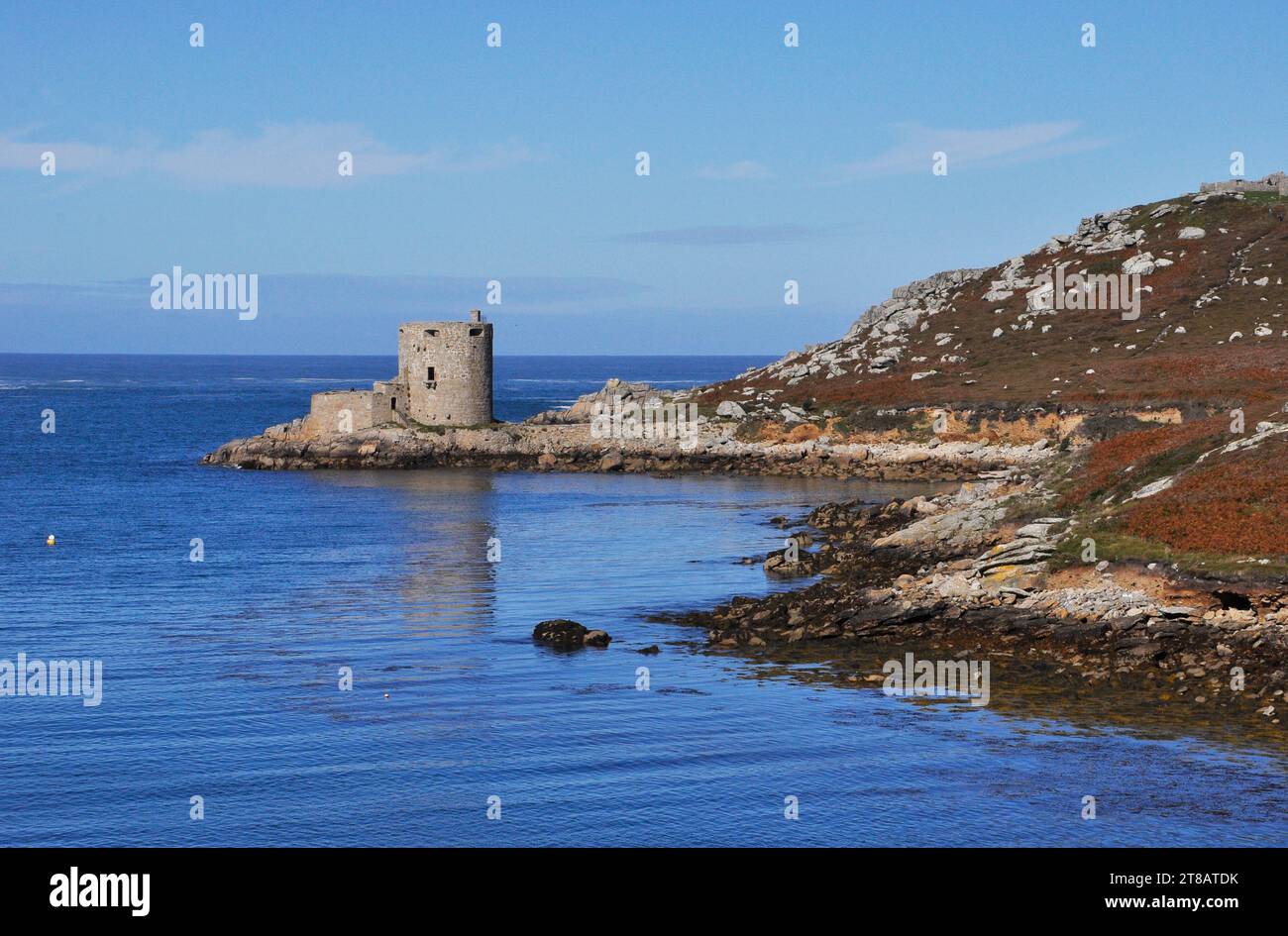 Ein Spiegelbild der Burg Cromwells auf Tresco im ungewöhnlich ruhigen Meer zwischen der Insel und Bryher auf den Scilly-Inseln. Das blaue Meer plätschert leise Stockfoto