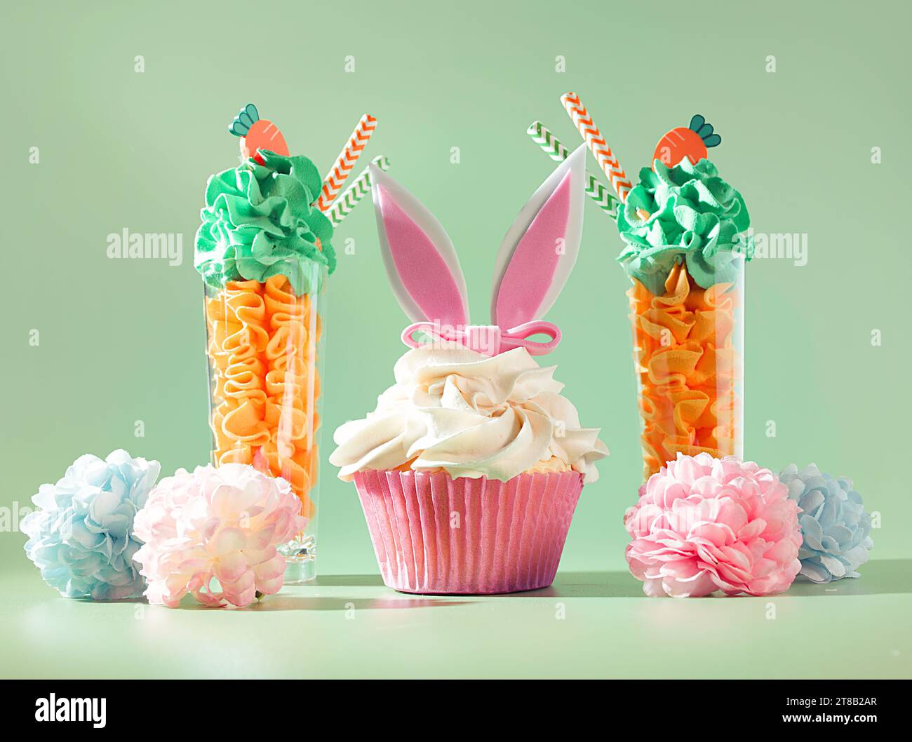 Frühlingsdesserts: Parfaits und Cupcakes mit Hasenohren auf pastellfarbenem Hintergrund Stockfoto