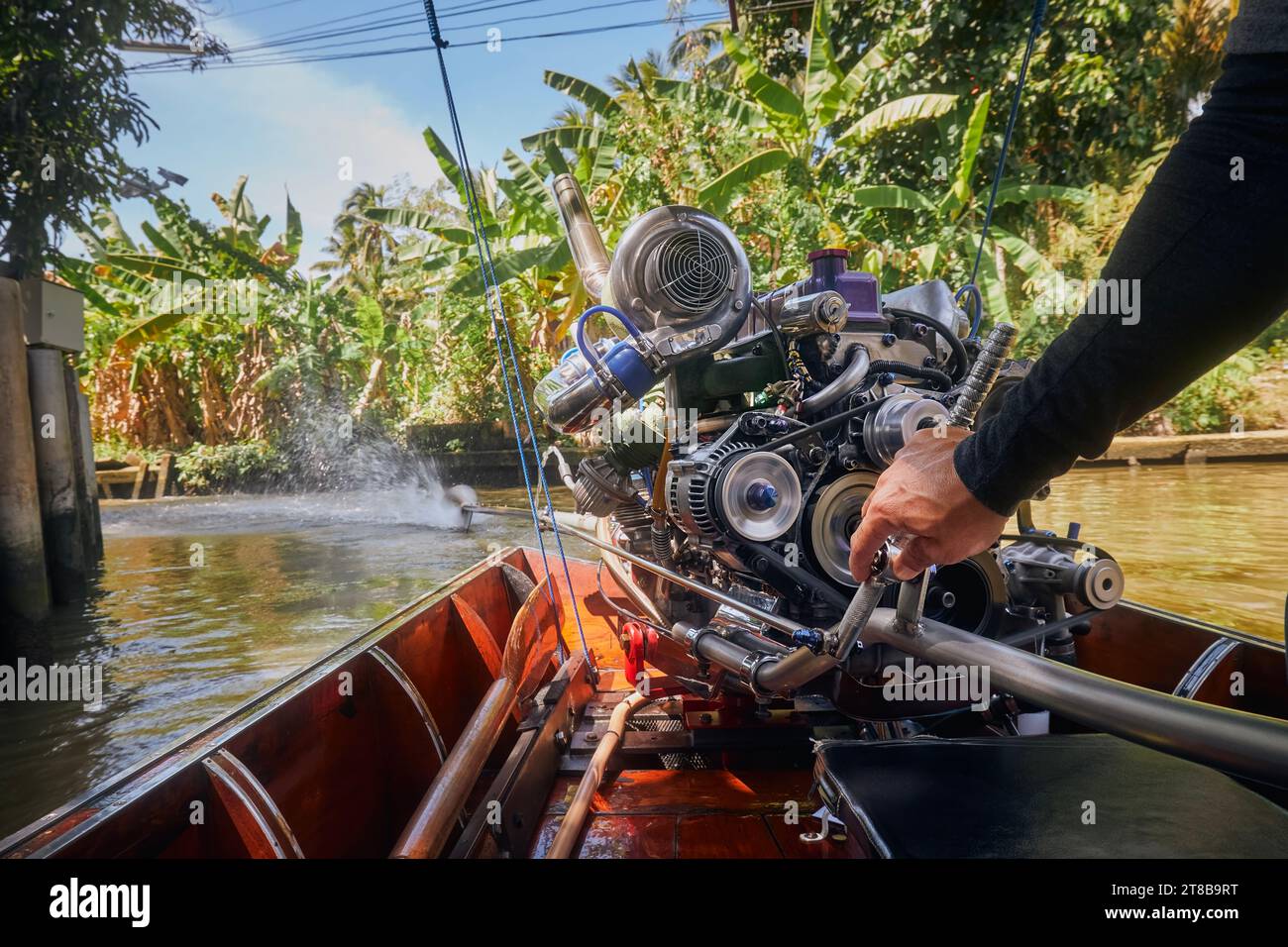 Leistungsstarker Motor eines traditionellen Langboot in Thailand. Hand-of-Drive-Steuerboot in schmalen Wasserkanal, der zum schwimmenden Markt Damnoen Saduak führt. Stockfoto